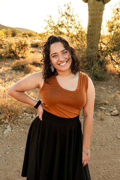Curly hair maternity, newborn and family photographer smiling in desert at sunset