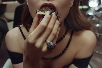 Close up portrait of a woman with a caviar appetizer in her hand positioned to her mouth