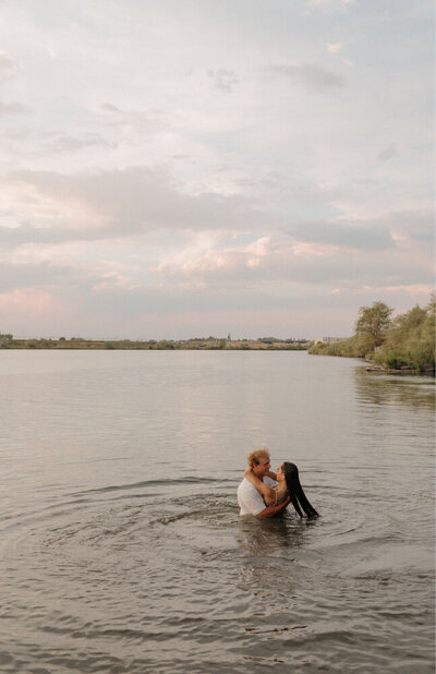 A man and woman in love are holding each other, standing in a lake together.