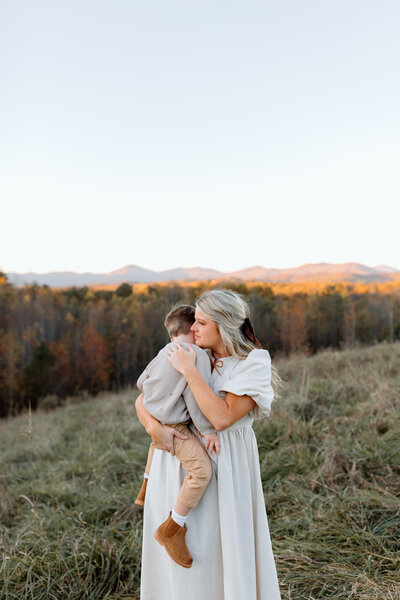 Mom holding her son and looking into the sunset.