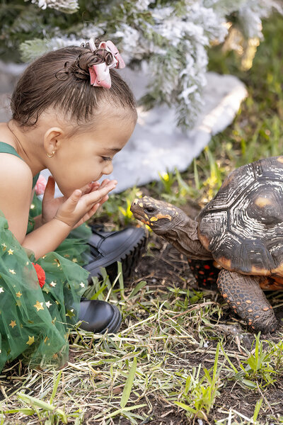 photo of a toddler blowing kisses at her pet tortoise