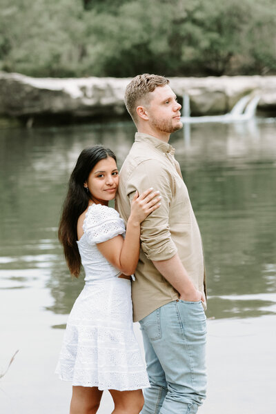 Couple taking engagement photos by waterfall at Mckinney Falls