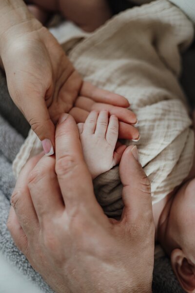 Nahaufnahme von den Händen eines Babys und dessen Eltern