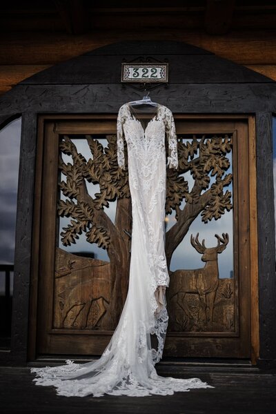 Bride's dress hangs from grand doorway of Colorado Airbnb.