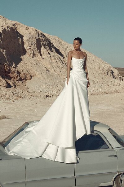KYHA BRIDE 'Evans' stocked at Sunday's Bride London, UK. Your search for the ultimate sartorial statement ends with Evans. A lesson in the art of draping, Evans features a structured, scoop neck bodice with directional draping and a draped column-meets-ballgown skirt. Evans' sculptural aesthetic cuts a close silhouette thanks to its lace up closure. Crafted from luxe and luminous duchess satin, Evans will prove to be an enduring masterpiece for the best-dressed set.