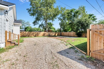 Gravel driveway behind this three-bedroom, two-bathroom vacation rental house just 5 minutes from The Silos in downtown Waco, TX.