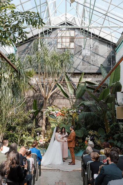 Bride and groom hold their hands high and smile joyfully as they walk back down the aisle after taking their wedding vows