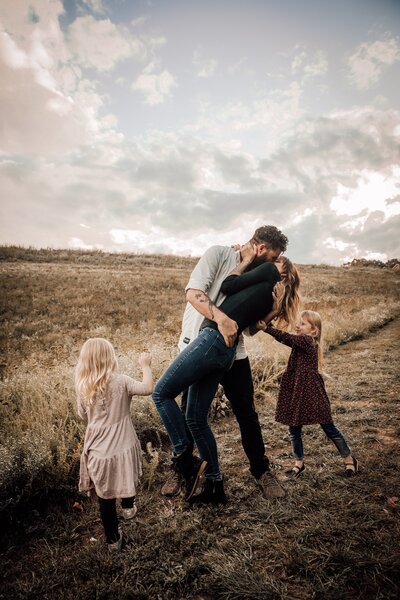 Parents embracing with daughters playing in field