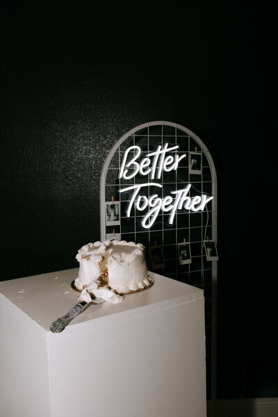 flash photo of a cute wedding cake with a neon sign backdrop during a texas wedding day