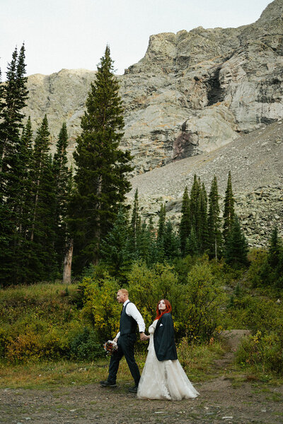 A couple exiting their wedding ceremony, cheering and dancing with their family and friends.