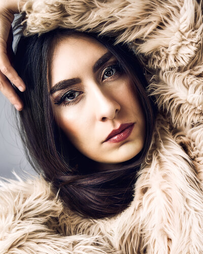 Woman in magazine-styled portrait with a fur jacket, dark hair and red lips