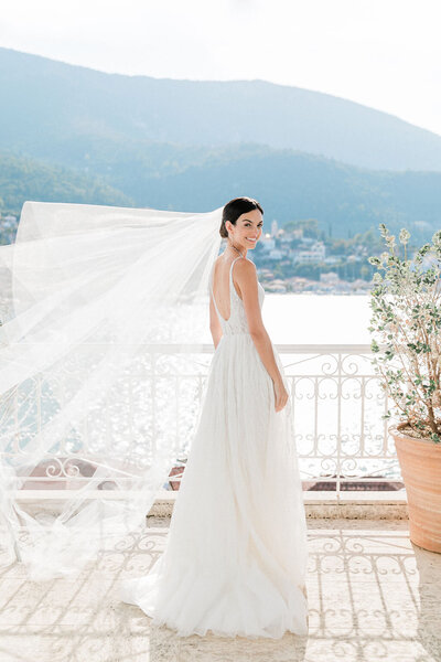 Bride standing with the Ionian Sea in the background, glowing in the sunshine on her wedding day.