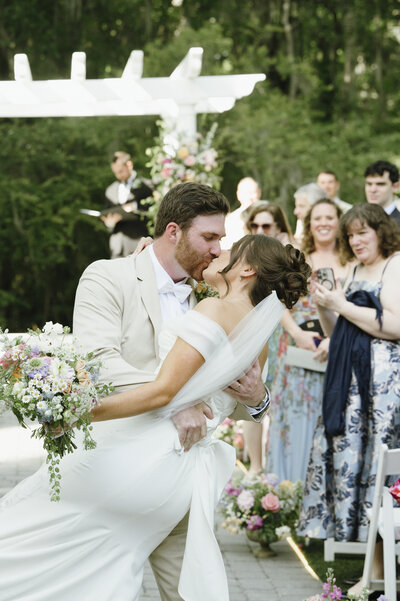 bride and groom kissing in aisle at wedding