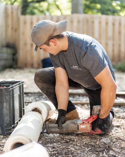 APS Waterproofing technician cutting PVC pipes for exterior drainage solutions in Atlanta, ensuring proper water management.