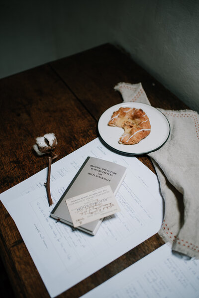 a flat lay is being styled, there is  a pastry, cotton bud, linen towel and worksheets