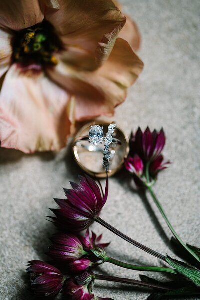 Stunning detailed wedding photography of engagement and wedding rings amongst florals