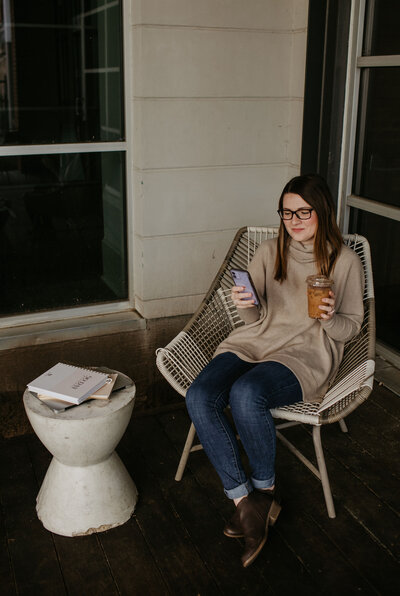 Woman checking her phone and drinking an iced chai latte