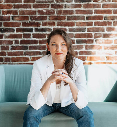 Elizabeth sitting on green couch with hands together