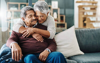elderly couple hugging on couch