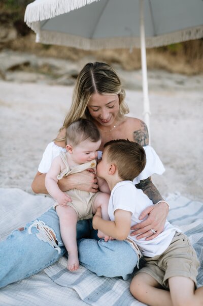 woman holding kids on the beach