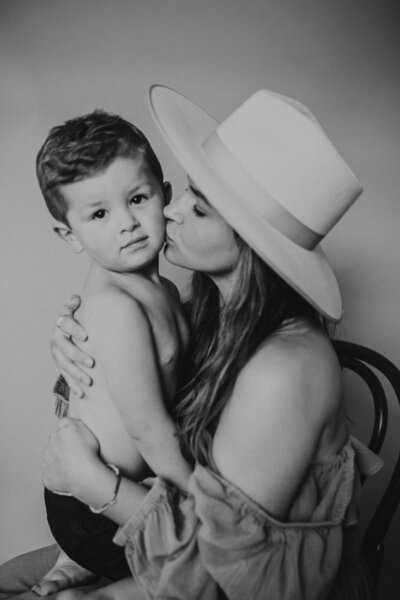 mom sweetly kisses her little boy on the cheek