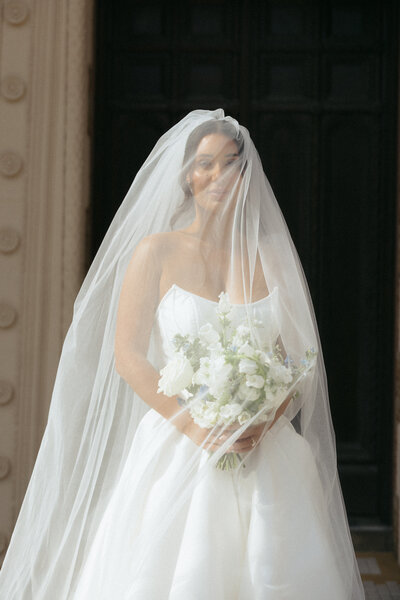 Candid photo of bride with the perfect lighting and her veil, a fleeting wedding day moment planned with intention by The Eventful Gals.