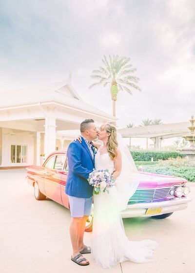 Newlywed couple kiss in front of vintage care Disney's Wedding Pavilion
