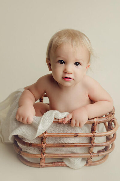 one year old boy sitting in a rattan basket