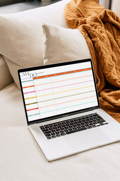 Mockup image of a laptop on a couch with an orange blanket in the background. On the laptop screen, is the Vendor Options spreadsheet