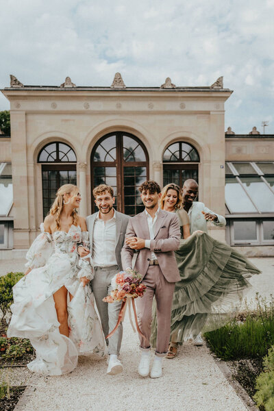Ein schwules Hochzeitspaar mit Brautstrauß, begleitet von zwei Bräuten – bunte, inklusive Hochzeitsfloristik aus der Ostschweiz.