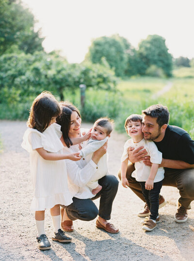 family with three young children laugh in candid family photo at discovery park captured by Seattle Newborn and Maternity Photographer