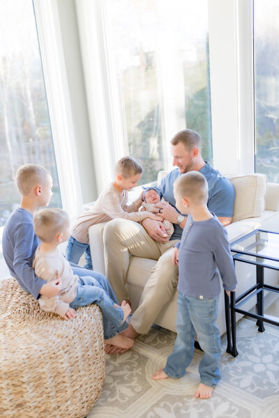 family gathered around holding baby sister with four brothers and dad louisville ky natural light