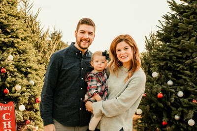 family of three at a Christmas tree farm