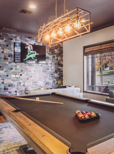 Modern game room at The Apex at Sky Valley featuring a pool table, bold lighting, and colorful tiled walls.