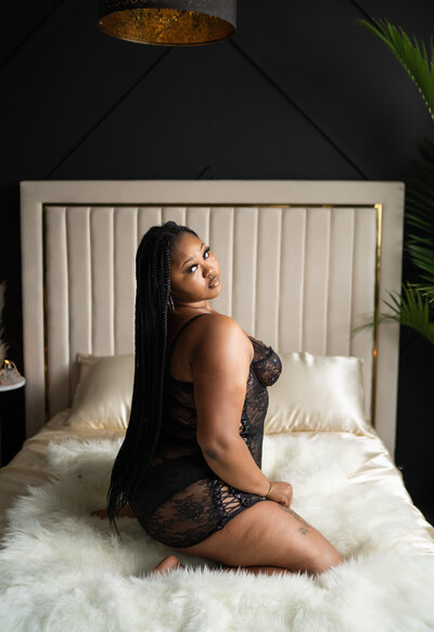 Beautiful woman sitting on the bed in a black lingerie coverup.