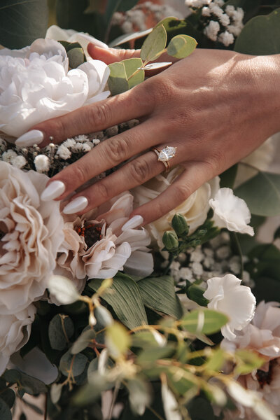 Close-up of a wedding bouquet featuring white roses and eucalyptus leaves, elegantly showcasing an engagement ring and matching wedding band, captured in a Pacific Northwest wedding detail photography session near Portland, Oregon.