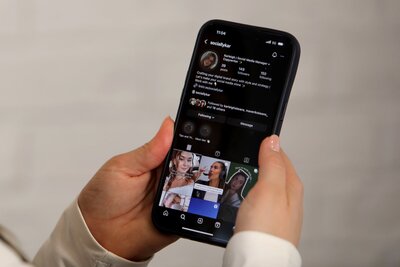 Karleigh Skeans holding an iphone with an Instagram feed shown for SociallyKar aka Brightside & Co.