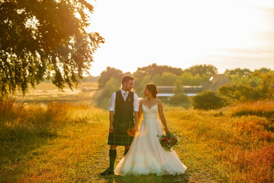 Asian Bride and Scottish Groom on a summers wedding day holding hands at Thorpe Garden.