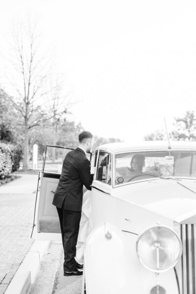 bride and groom kissing by vintage car after wedding