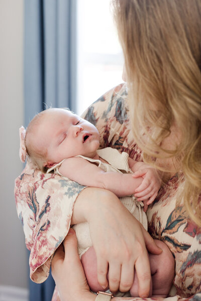 Mom looking down at sleeping baby in her arms during an in home shoot in Charlotte NC