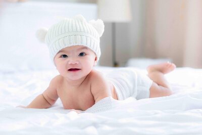 baby laying on bed smiling at the camera