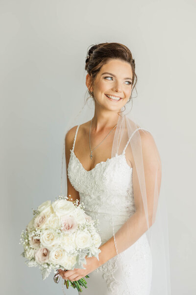 A beautiful and happy bride on her wedding morning holding her bouquet of flowers.