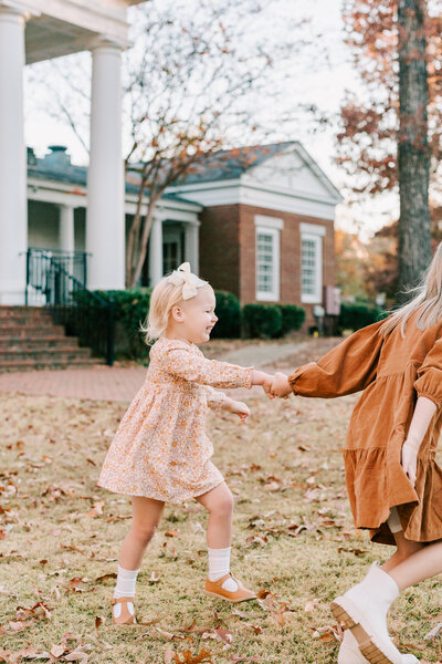 Two young sisters holding hands and running together during their family session.