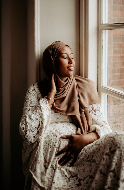 en gravid kvinna i hijab håller om sin mage under hennes gravidfotografering