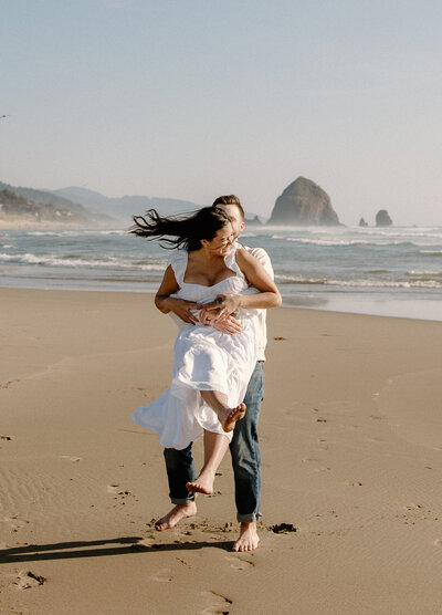 Groom spins his bride on the beach during their anniversary session