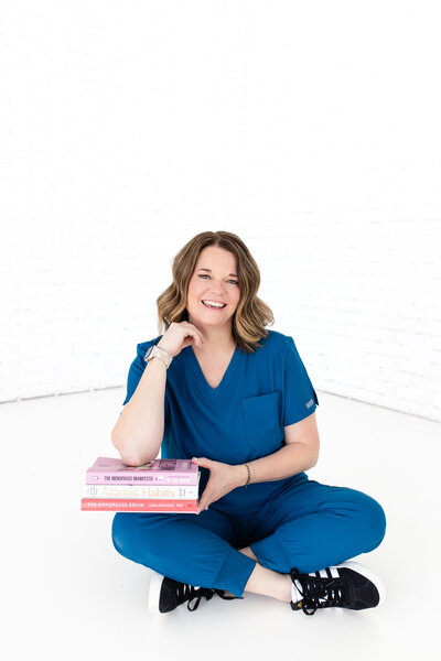 Our weight loss professional at Reforme Wellness, dressed in a blue nurse uniform, follows up after a patient visit while sitting on the white floor