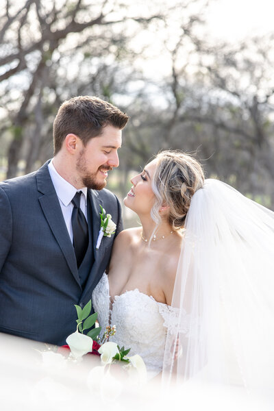 veil swoops in front of  photographer as couple lean in for a kiss at an East Texas winter wedding