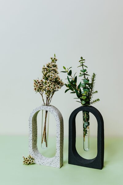 Two abstract vases hold greenery.