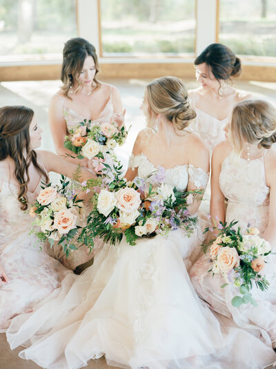 Bride sitting surrounded by her bridesmaids all holding bouquets