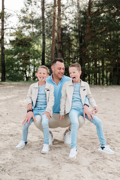 Twee grote zussen houden hun pasgeboren broertje liefdevol vast tijdens een newbornshoot, vastgelegd door Monica Stout Fotografie.